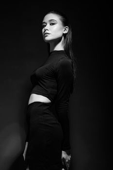 Elegant black and white portrait of a woman with a serious expression, captured in a studio.