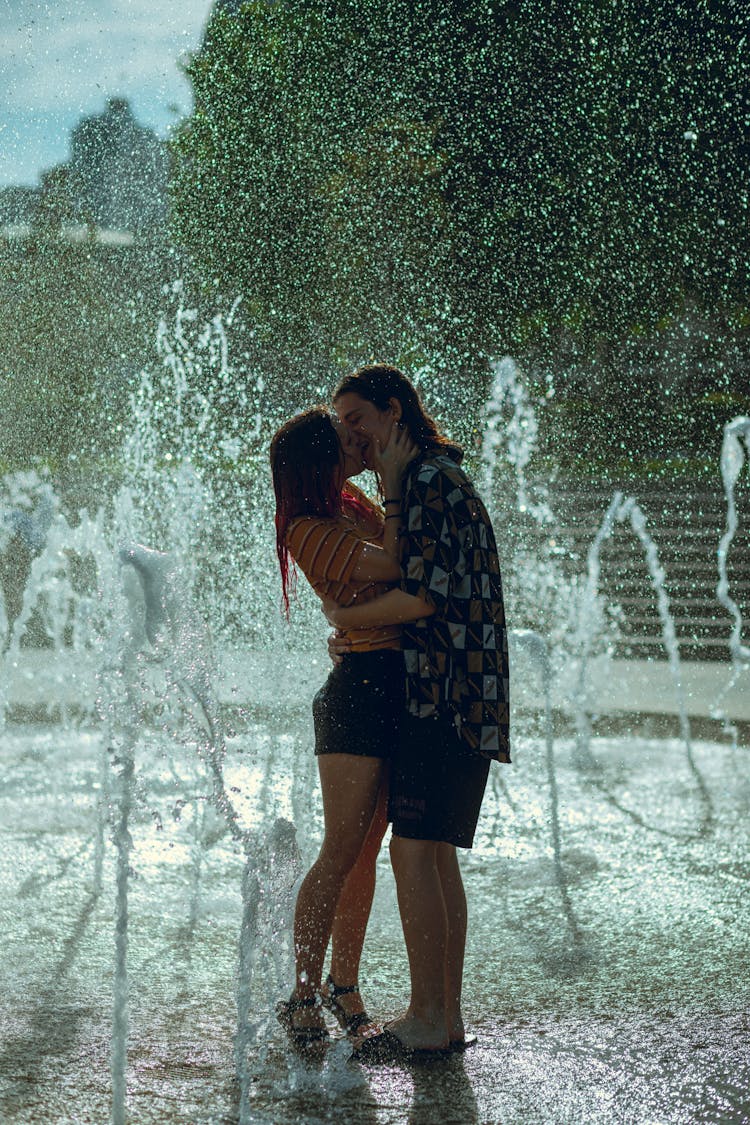 A Couple Standing On Water Fountain Kissing