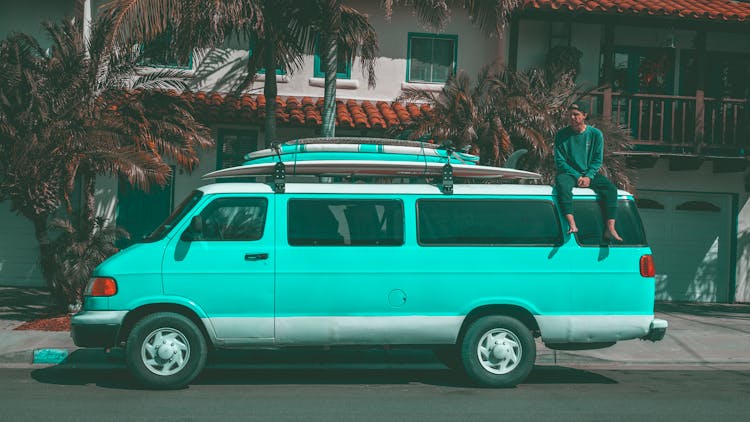 Man Sitting On Top Of Teal Dodge Ram Van Parked Near House