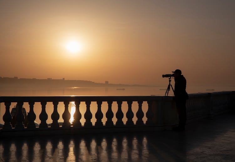 Silhouette Of A Person Using A Telescope On The Bridge