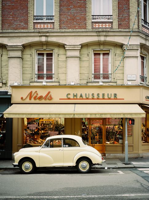 A vintage car parked outside a charming retro storefront on a historic city street.