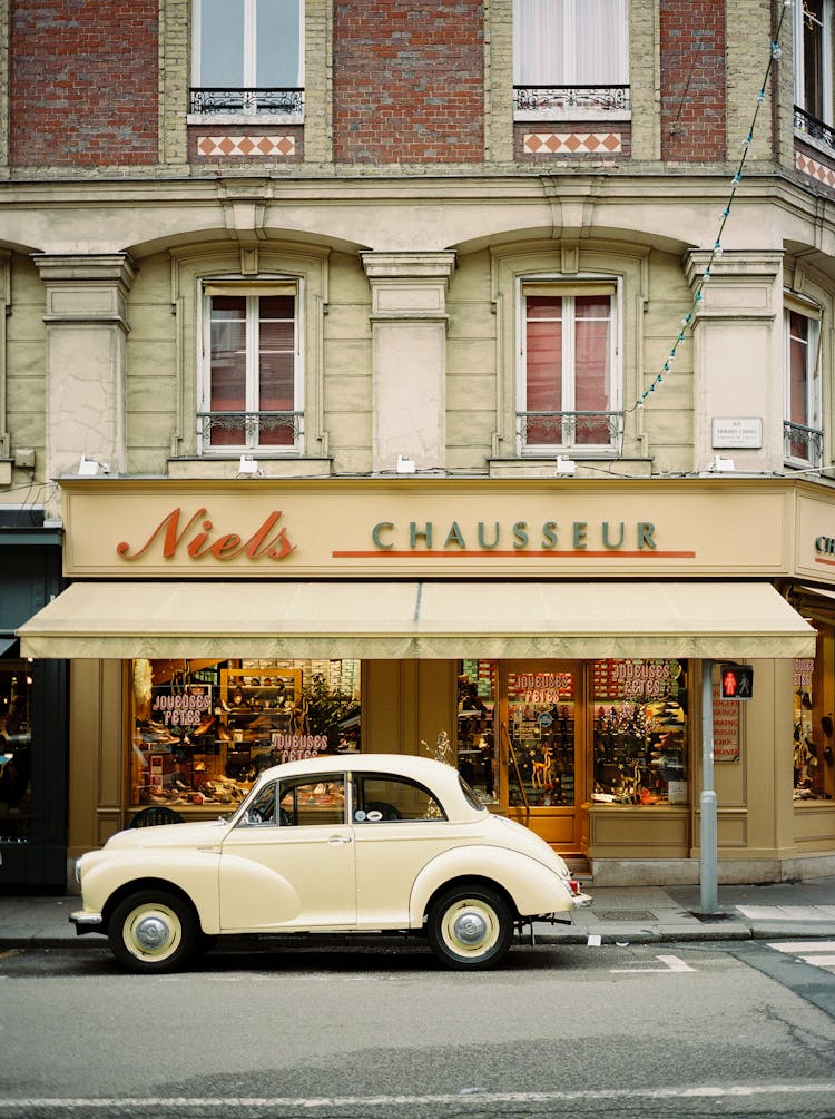 Vintage Car Parked In Front Of A Store In A Classical Building 