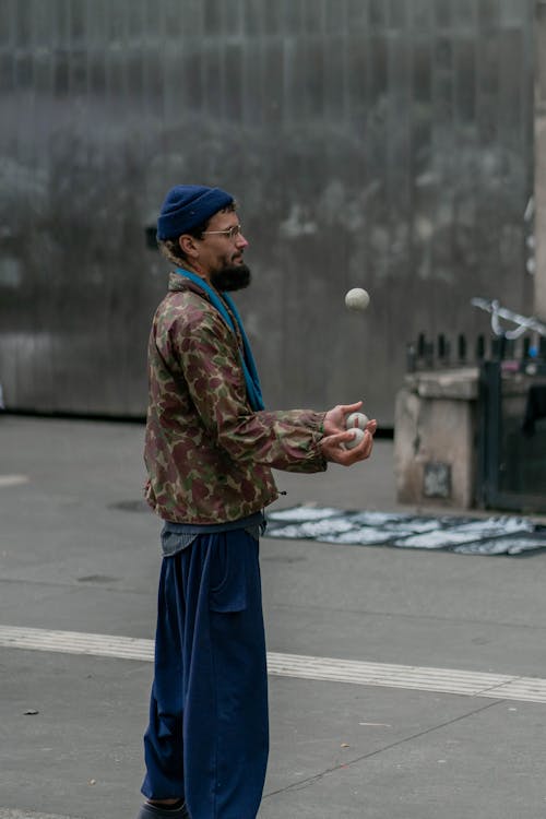 A Side View of a Bearded Man in Blue Pants Standing on the Street