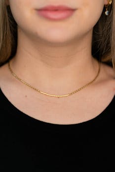 A sophisticated close-up showcasing a gold necklace elegantly worn by a woman, highlighting simple elegance.