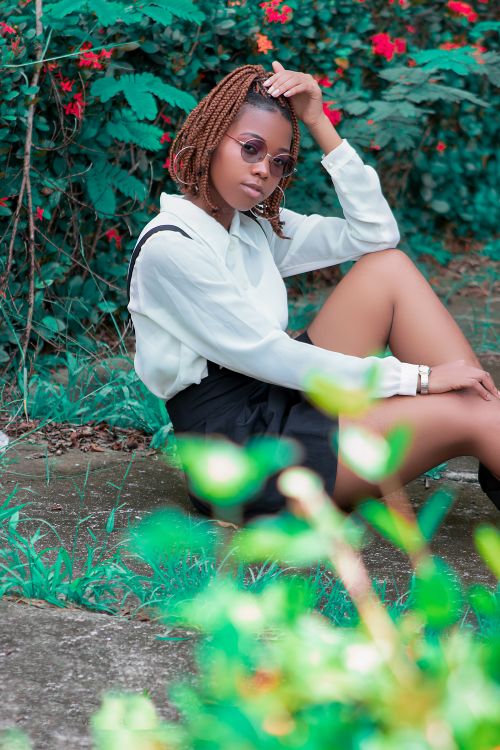 Free Fashionable woman with braided hair posing outdoors in sunglasses and white blouse. Stock Photo
