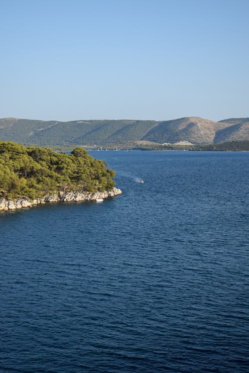 An Aerial Photography of an Ocean Near the Island and Mountain Under the Blue Sky