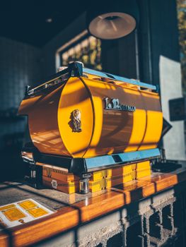 Stylish yellow espresso machine in a cozy café ambiance with warm lighting.