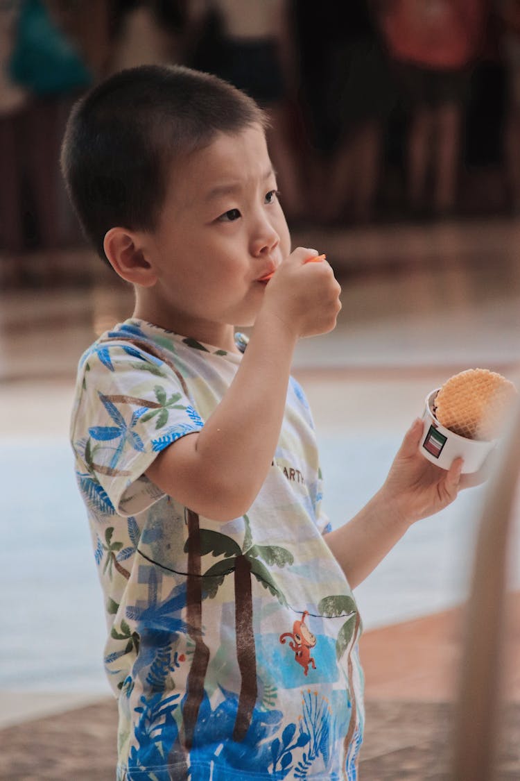 A Boy In Printed Shirt Eating An Ice Cream