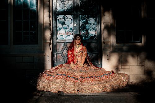 Free A stunning bride in a traditional bridal gown poses elegantly by an ornate doorway, showcasing intricate jewelry. Stock Photo
