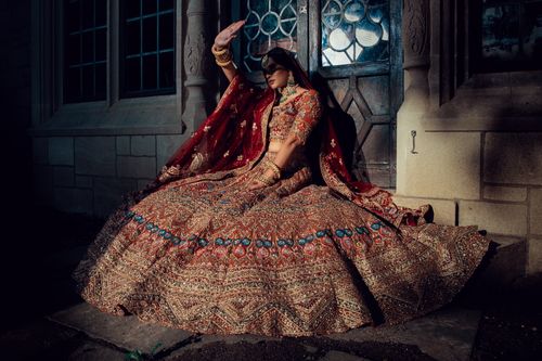 Free Stunning portrait of a bride in an intricately designed traditional Indian lehenga, sitting elegantly in a photoshoot. Stock Photo