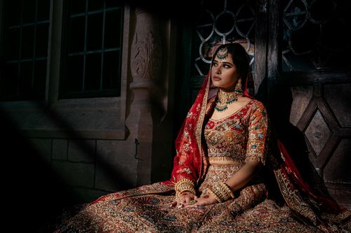 Free Elegant South Asian bride wearing a red and gold embroidered lehenga. Stock Photo