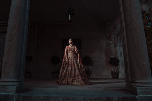 Free Woman in an ornate dress standing in a grand architectural setting, exuding elegance. Stock Photo