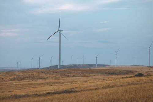 White Wind Turbines on Brown Grass Field Under Blue Sky