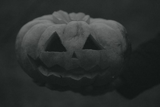 A detailed grayscale close-up of a carved pumpkin, perfect for Halloween themes.