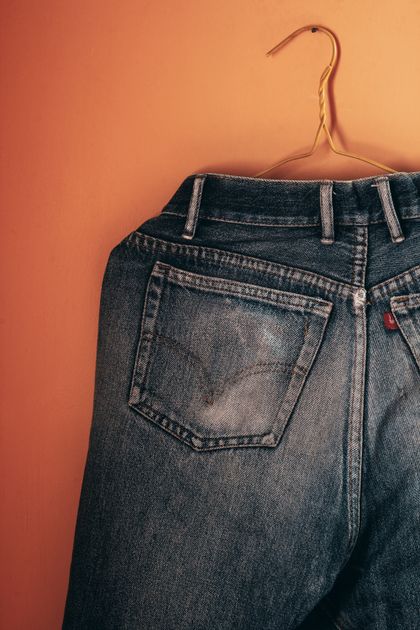 Denim jeans hanging against a plain backdrop — photo by Arturo Añez on Pexels