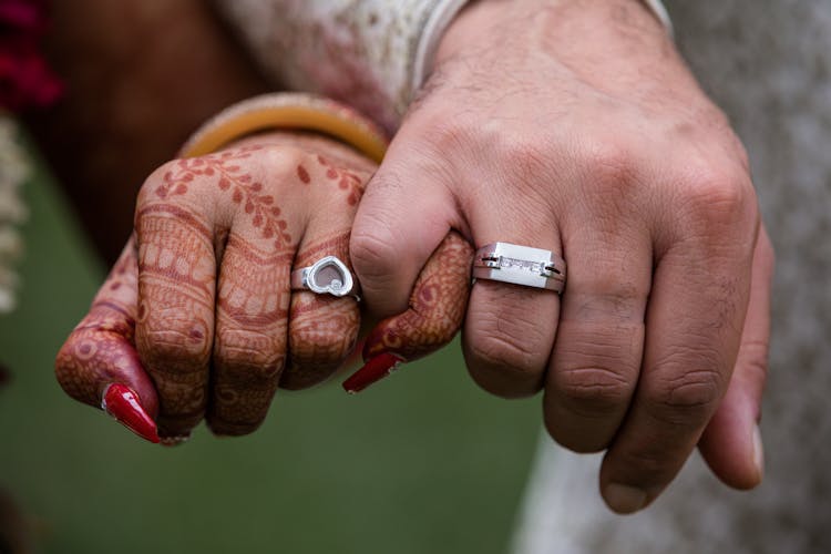 A Bride And Groom's Hands Holding Pinky's Together