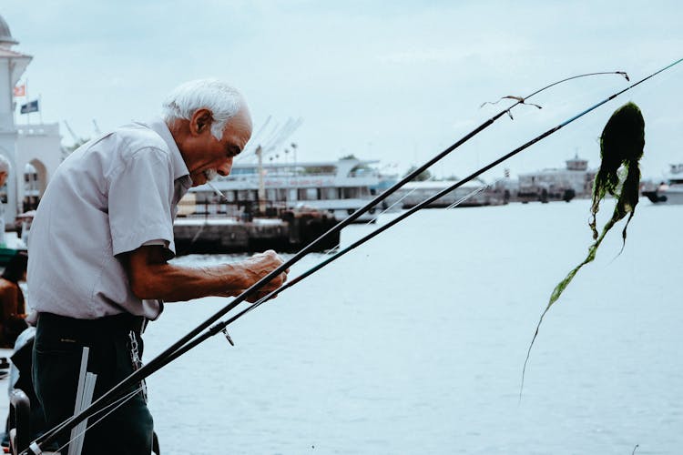 Elderly Man Fixing A Fishing Rod