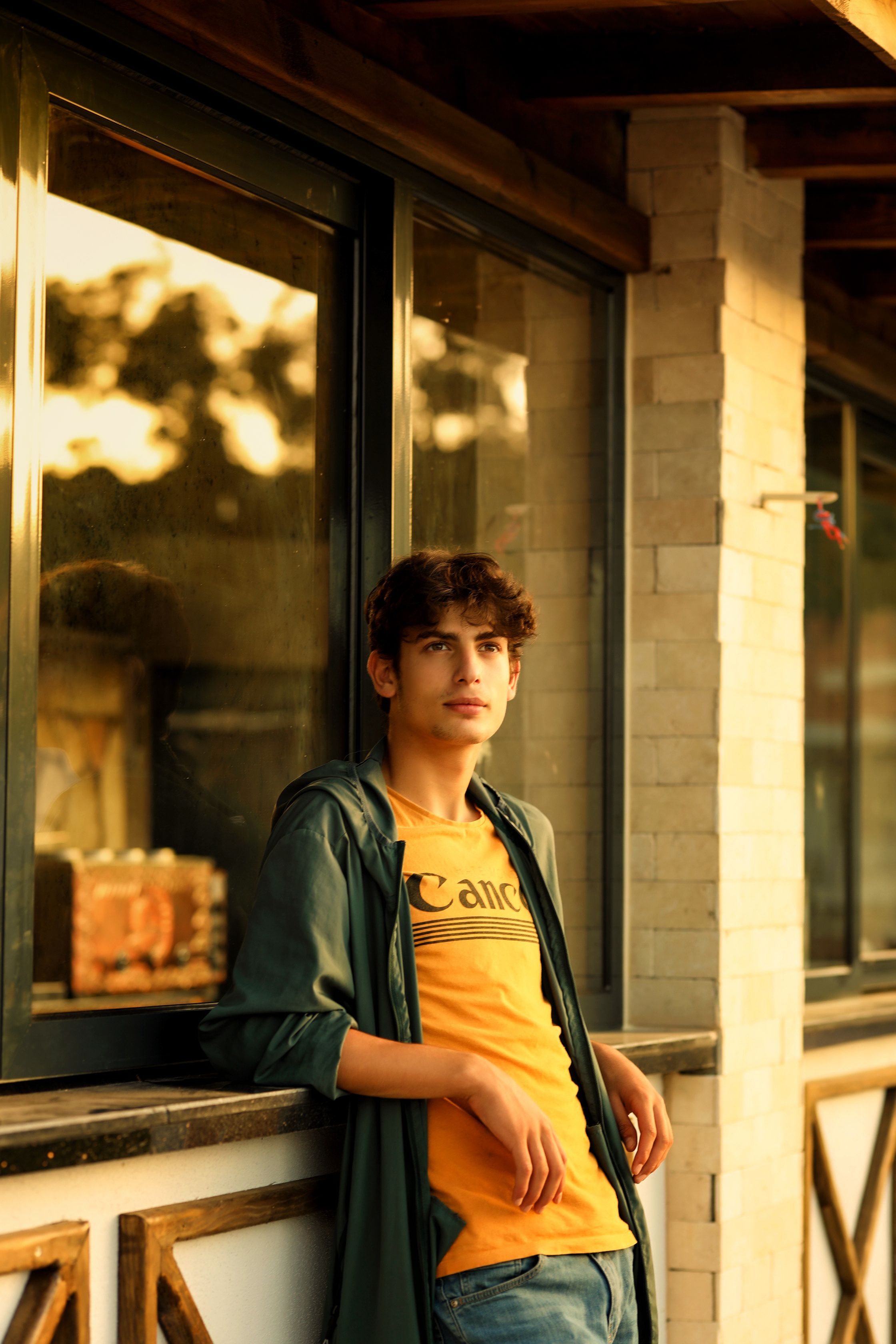 Stylish young man leaning against an urban wall during sunset.