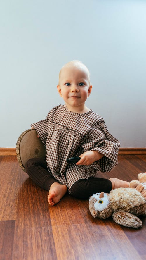 Baby Sitting on Hardwood Floor with Plush Toy