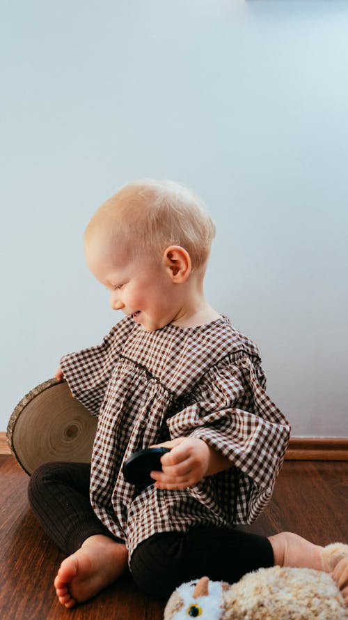 Laughing Baby Sitting on Floor Next to Plush Toy