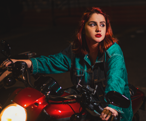 Free A stylish woman in a denim jacket confidently rides a motorcycle in the evening. Stock Photo