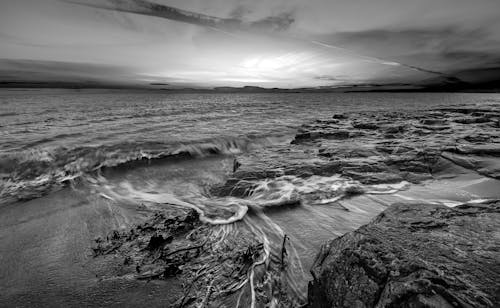 A Grayscale Photo of Beach Waves Crashing on Shore