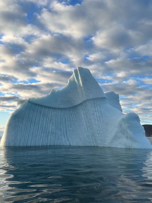 Free A stunning iceberg floating in the serene waters of the Arctic under a cloudy sky. Stock Photo