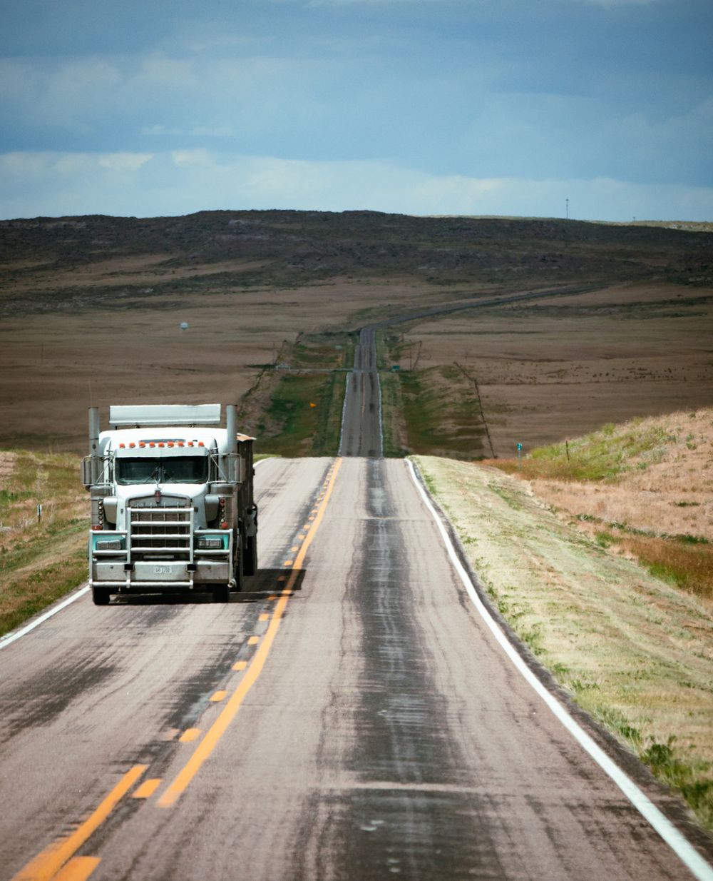 A semi truck covering long highway miles toward the horizon