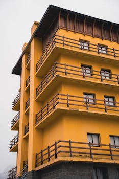 Vertical shot of a modern yellow apartment building with wooden railings and concrete structure.