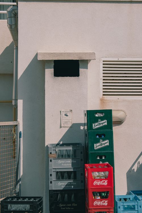 Free Colorful beverage crates stacked against a building wall in IB, Spain under daylight. Stock Photo