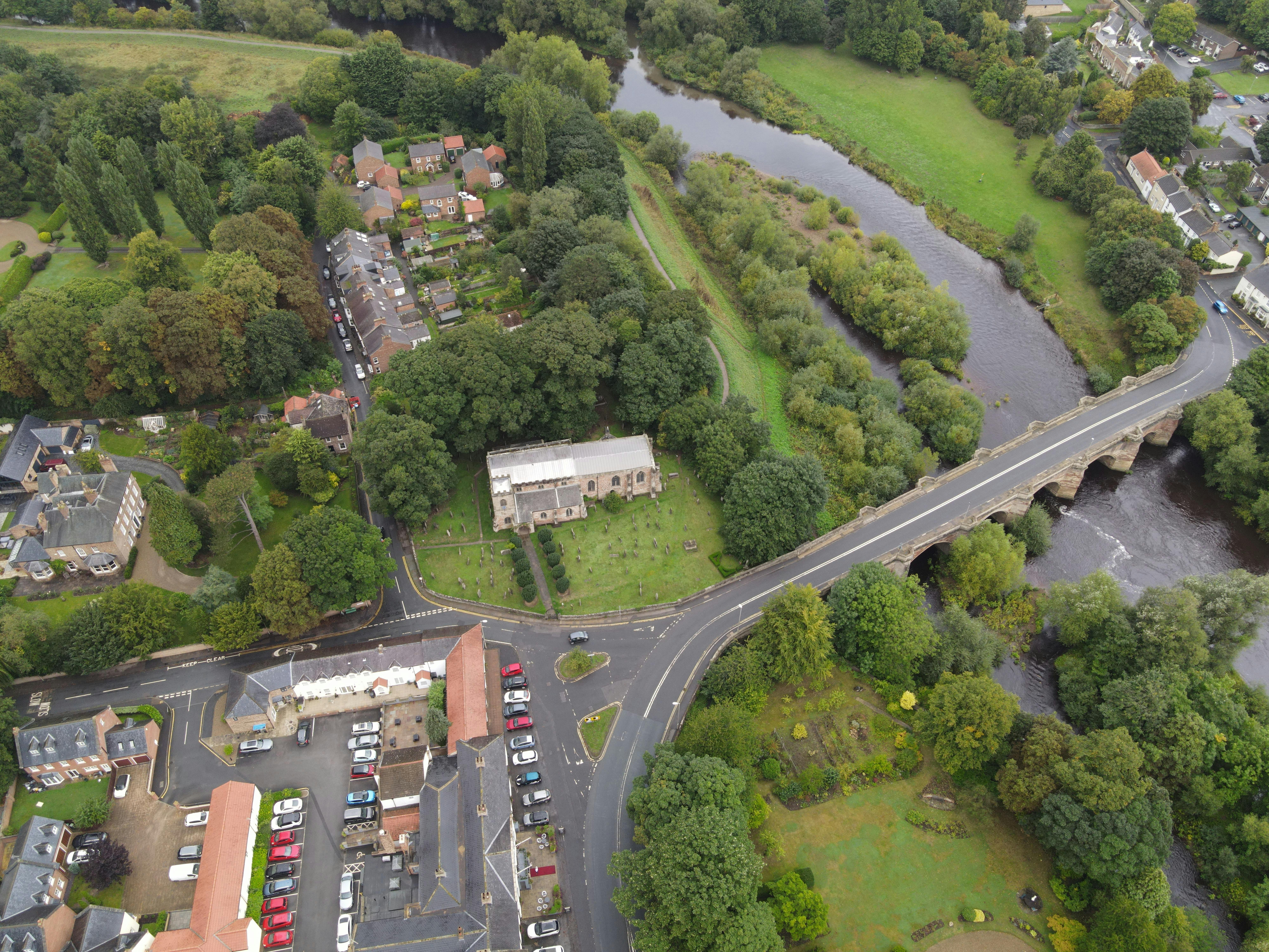 Aerial shot showcasing a river winding through a lush green urban area.
