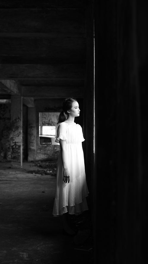 Free Black and white portrait of a girl in a white dress standing in an abandoned building. Stock Photo