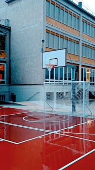 A wet basketball court beside a school building in Verona, Italy, during daytime.