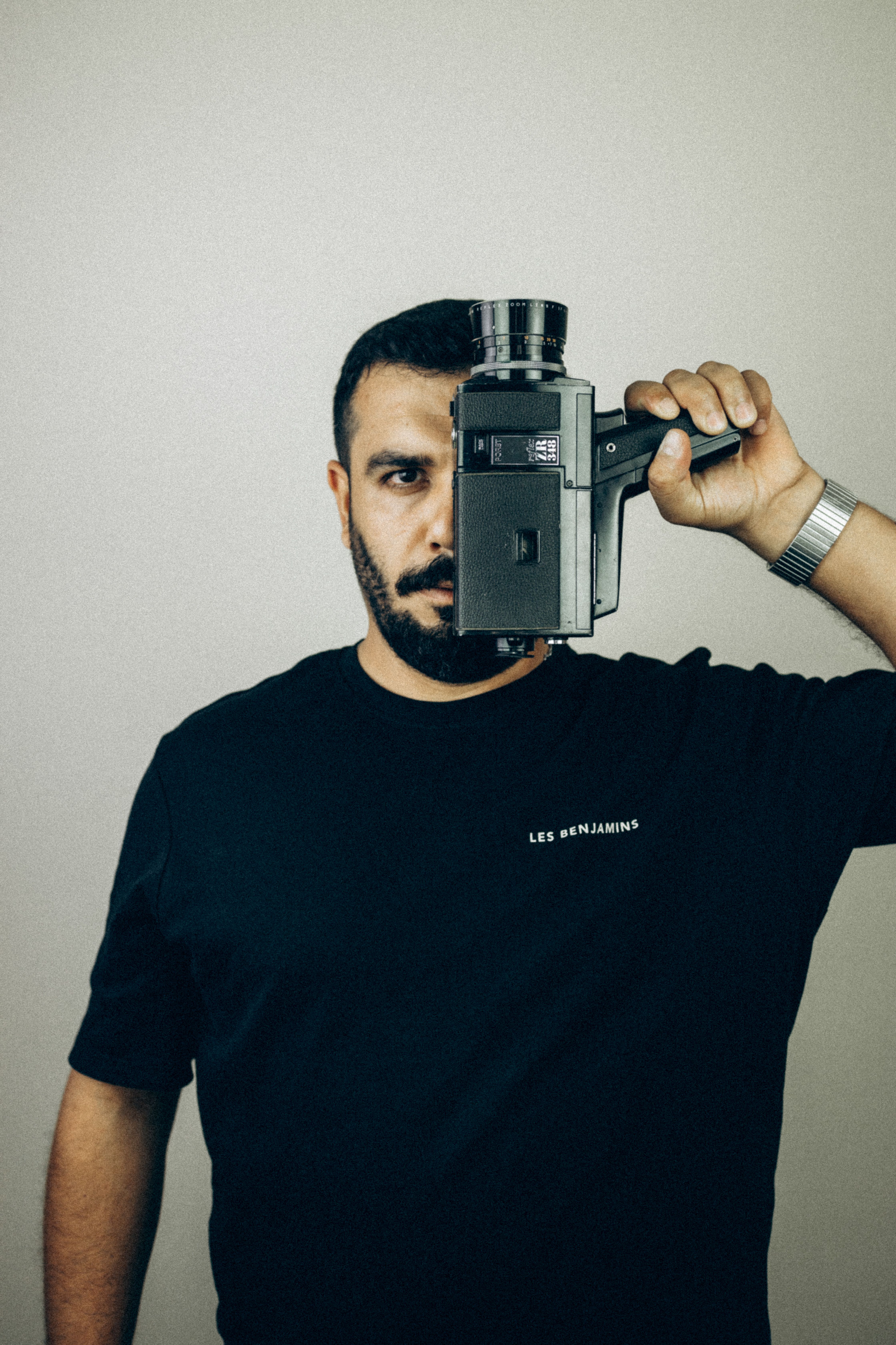 Portrait of a man holding a vintage camera with a serious expression.