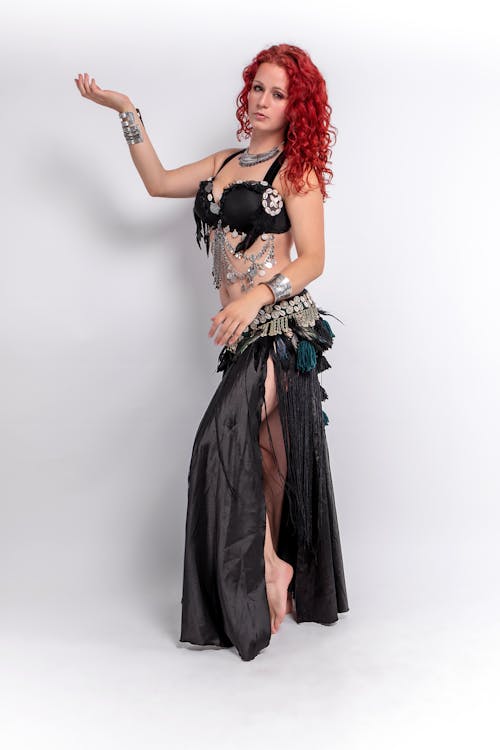 Woman with Red Hair Wearing Black Sexy Outfit Standing Near white Wall while Posing at the Camera