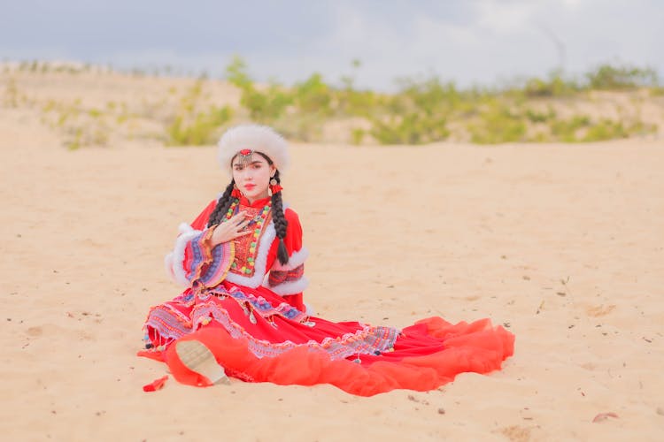 Young Woman Posing In Traditional Mexican Clothes Sitting On A White Sand