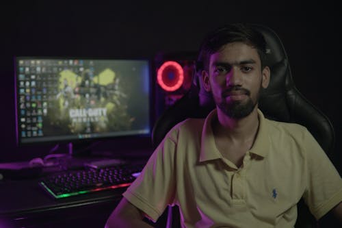 A Bearded Man Sitting on a Gaming Chair Near Table with Computer Set-Up