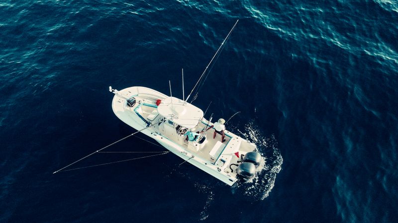 Aerial view of a center console fishing boat trolling with outriggers in deep offshore water