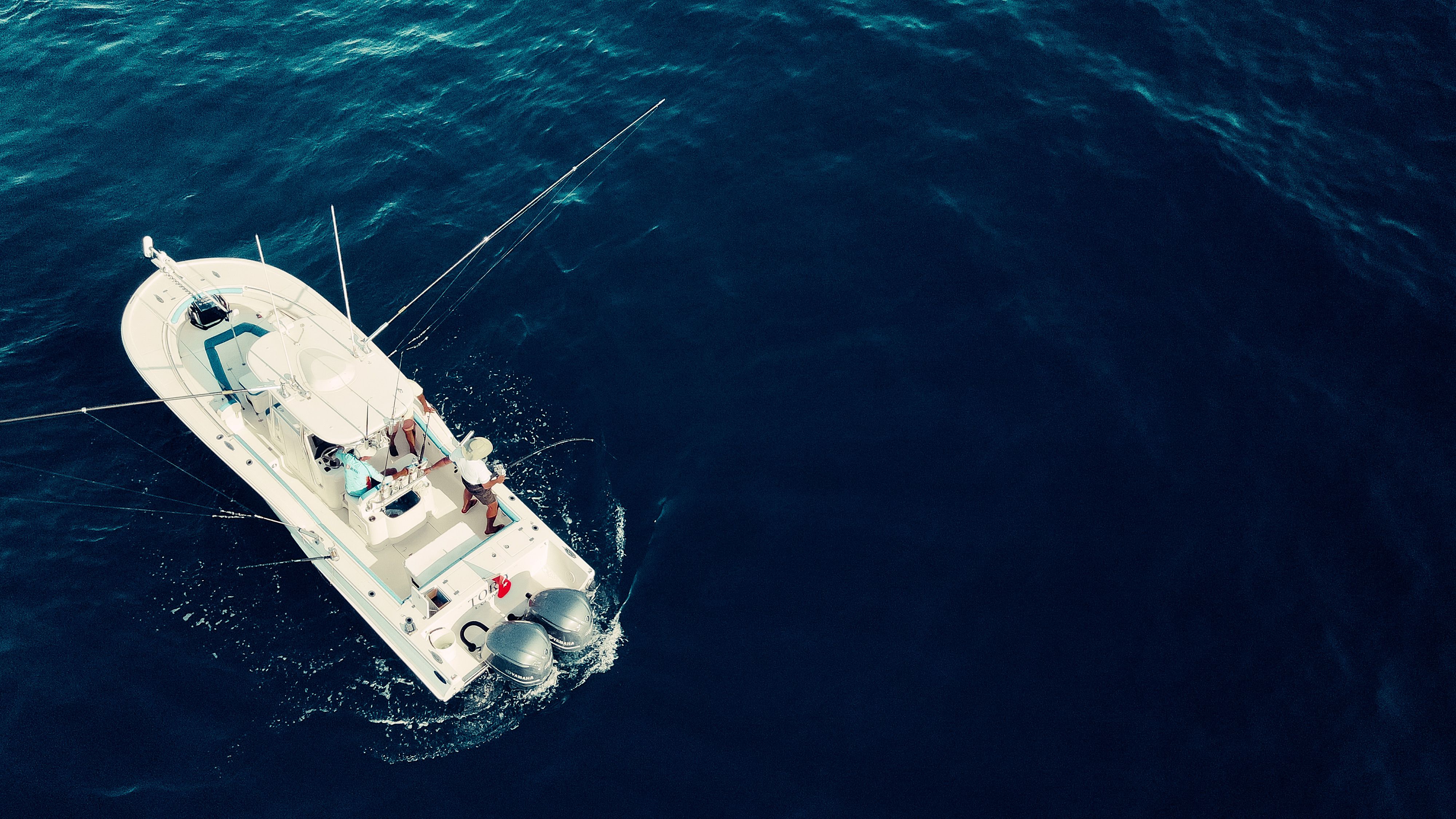 Aerial view capturing a lone yacht sailing across the deep blue ocean waters.