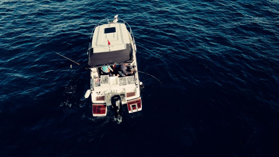 Vista aérea de una lancha de pesca con anglers en aguas azules profundas