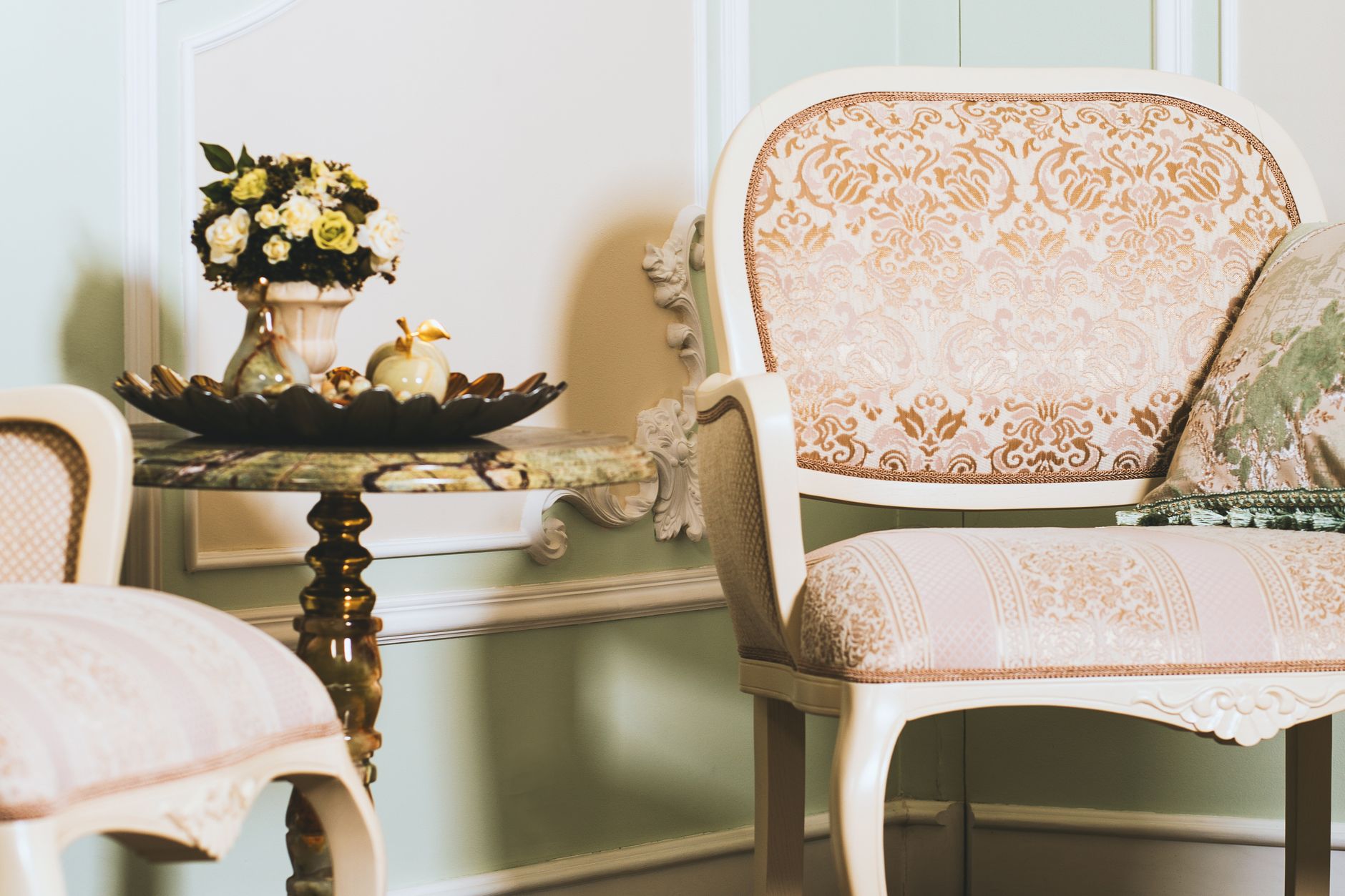 A beautifully styled vintage interior featuring ornate chairs, a marble table, and elegant decor.