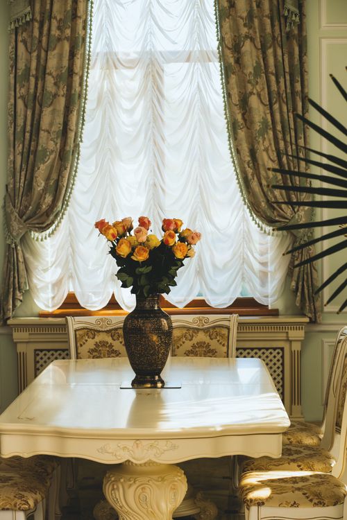 Free Luxurious dining room interior featuring ornate furniture and a floral centerpiece on the table. Stock Photo