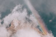 空中捕捉到了一座被雾笼罩的山峰，上面有充满活力的彩虹，令人惊叹