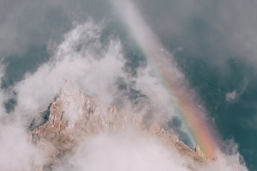 空中捕捉到了一座被雾笼罩的山峰，上面有充满活力的彩虹，令人惊叹