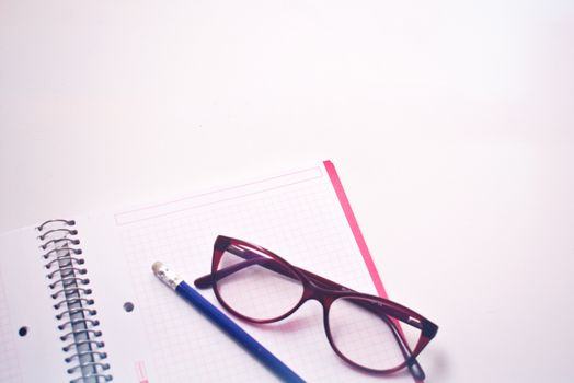 Eyeglasses resting on graph paper notebook with pencil, perfect for study or writing concepts.