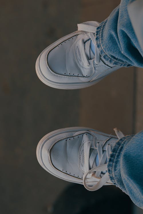 A Person in Denim Jeans Wearing White Sneakers