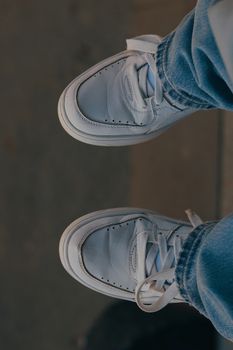 Close-up view of white sneakers paired with denim jeans, showcasing urban street fashion.