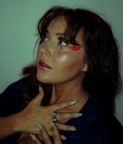 Free Portrait of a woman with bold eyeshadow and painted nails, striking a pose. Stock Photo