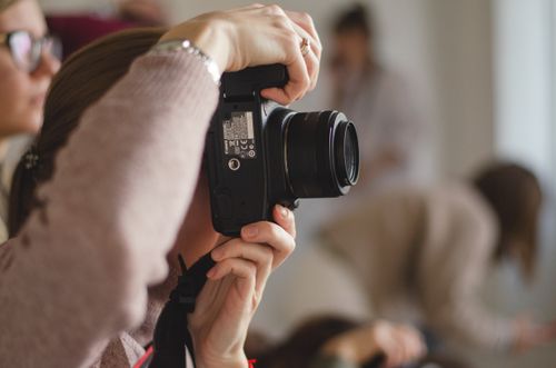 Free A focused female photographer capturing moments with her DSLR camera in an indoor setting. Stock Photo