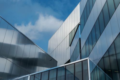 Free Low angle view of modern glass buildings reflecting blue sky and clouds. Stock Photo